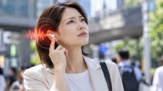 街中でイヤホンに触れる女性と、耳の周りに赤い音波を重ねたイメージ画像